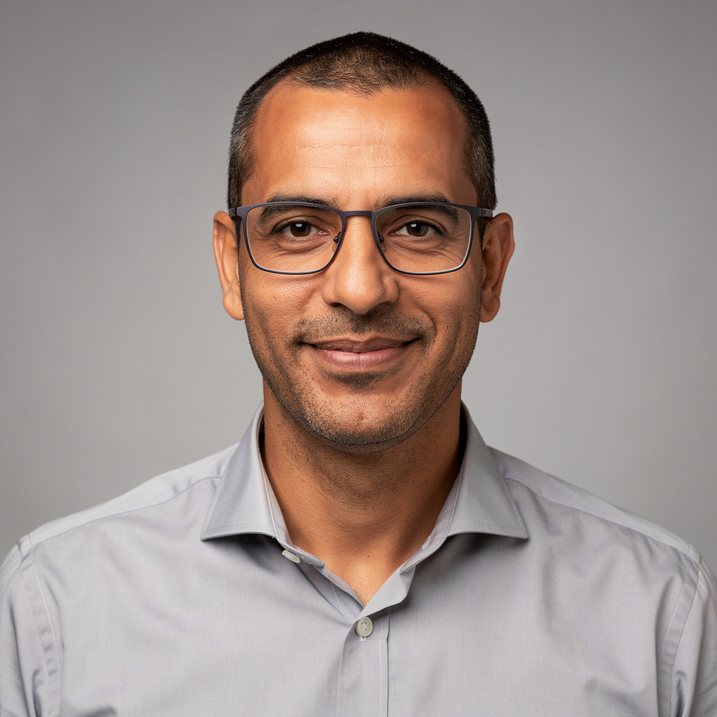 Studio portrait of a professional man with short dark hair and glasses